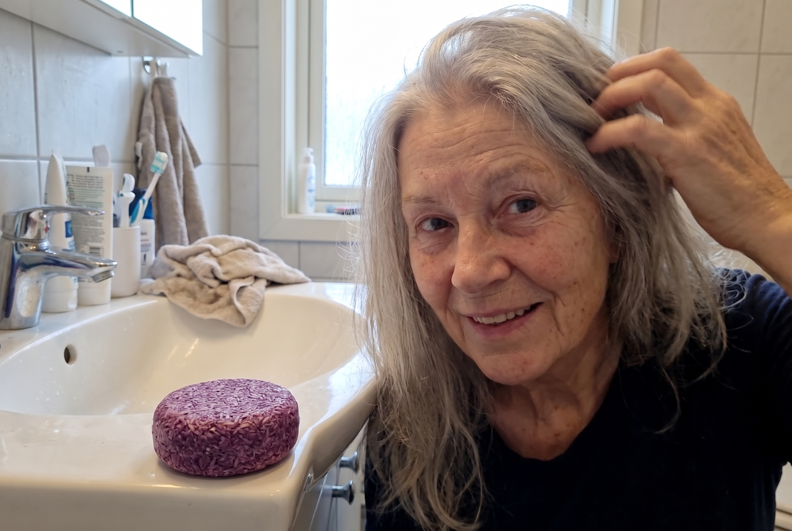 Eldre norsk kunde tar selv en selfievideo mens hun viser håret etter bruk av Julie Rosmarin Sjampobar
