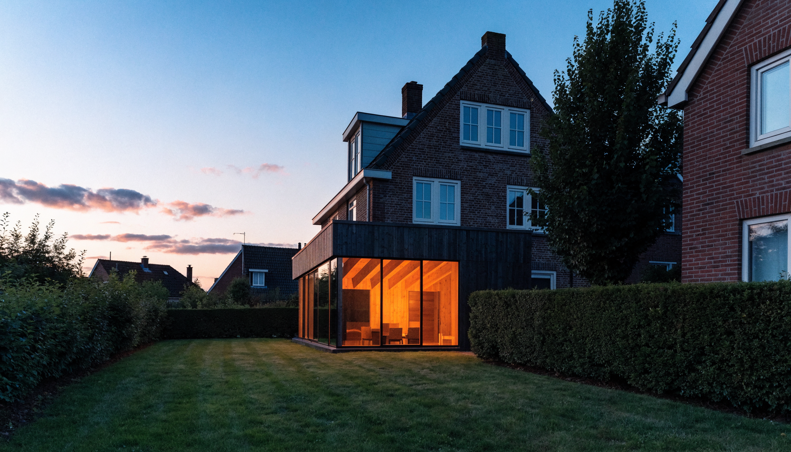 Woning in Breda met nieuwe aanbouw van hout en glas, in de avond