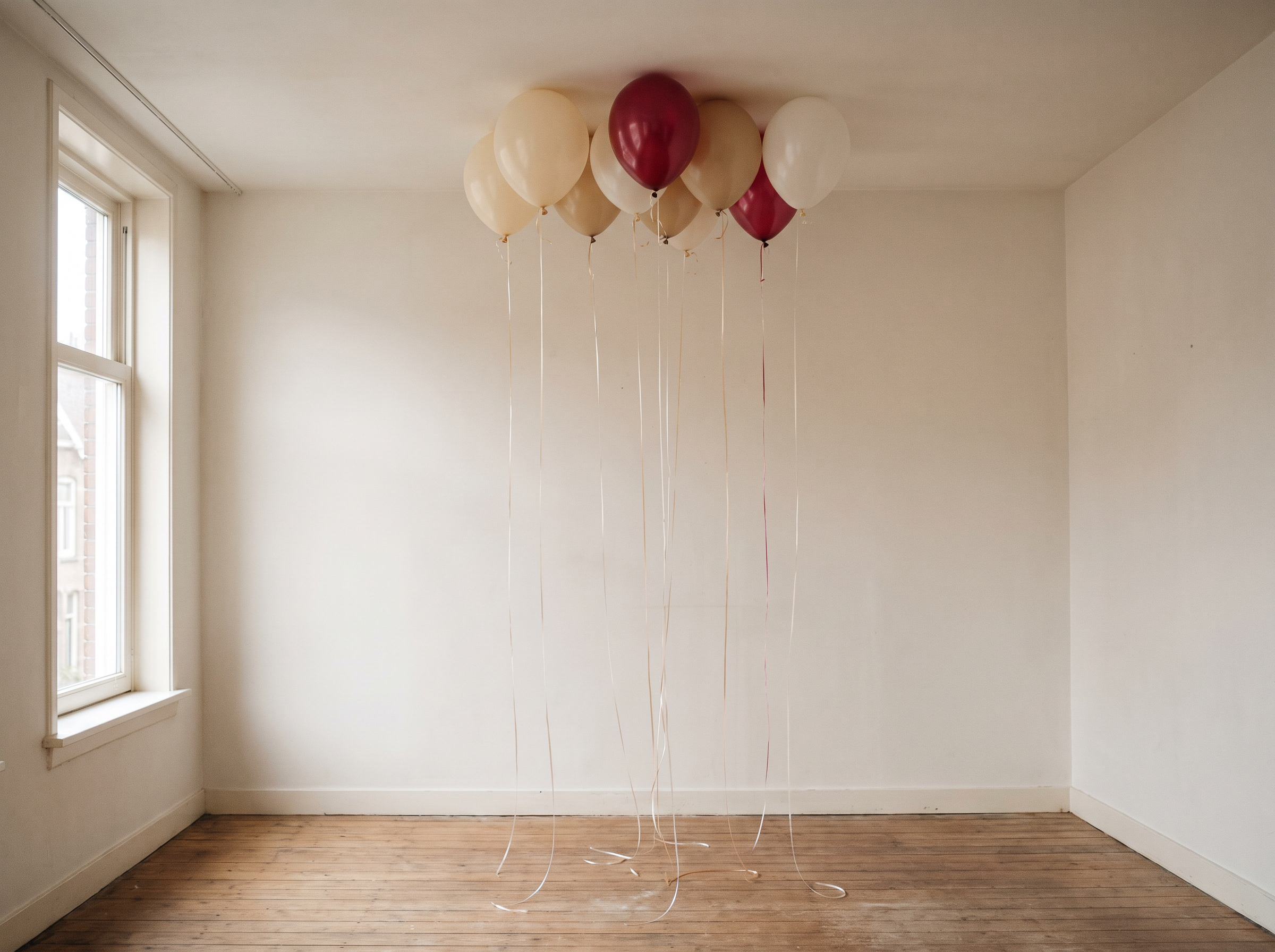 Heliumballonnen met linten bij een raam