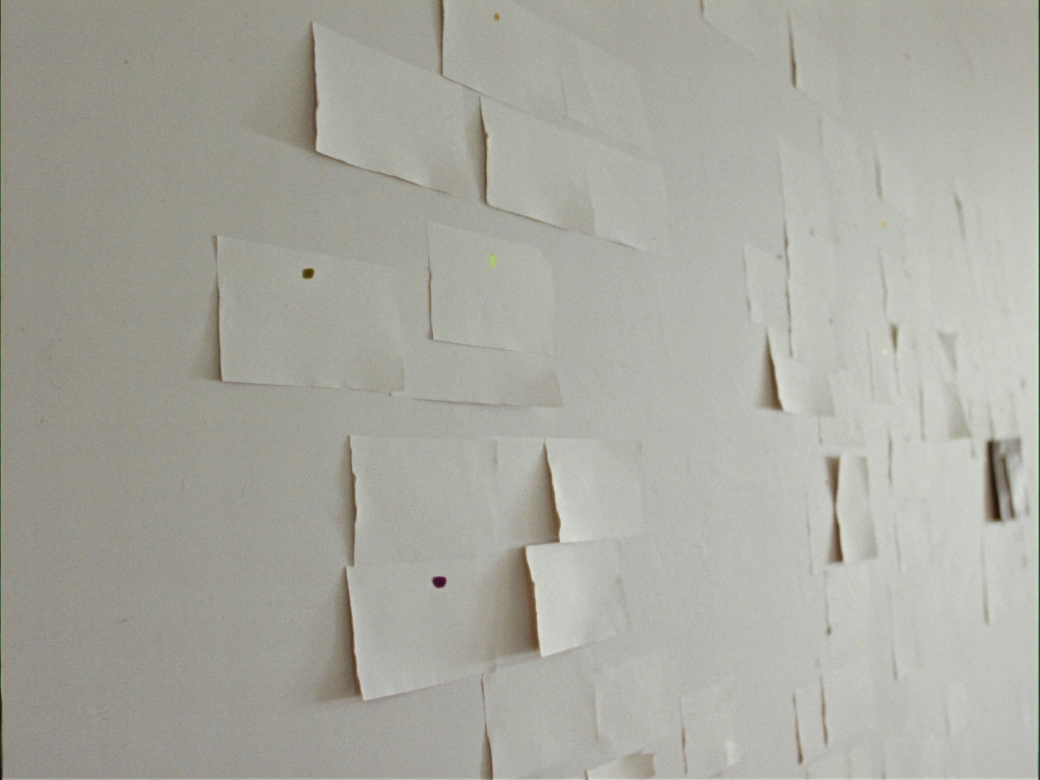 Wall of clustered blank paper cards with a few coloured voting dots