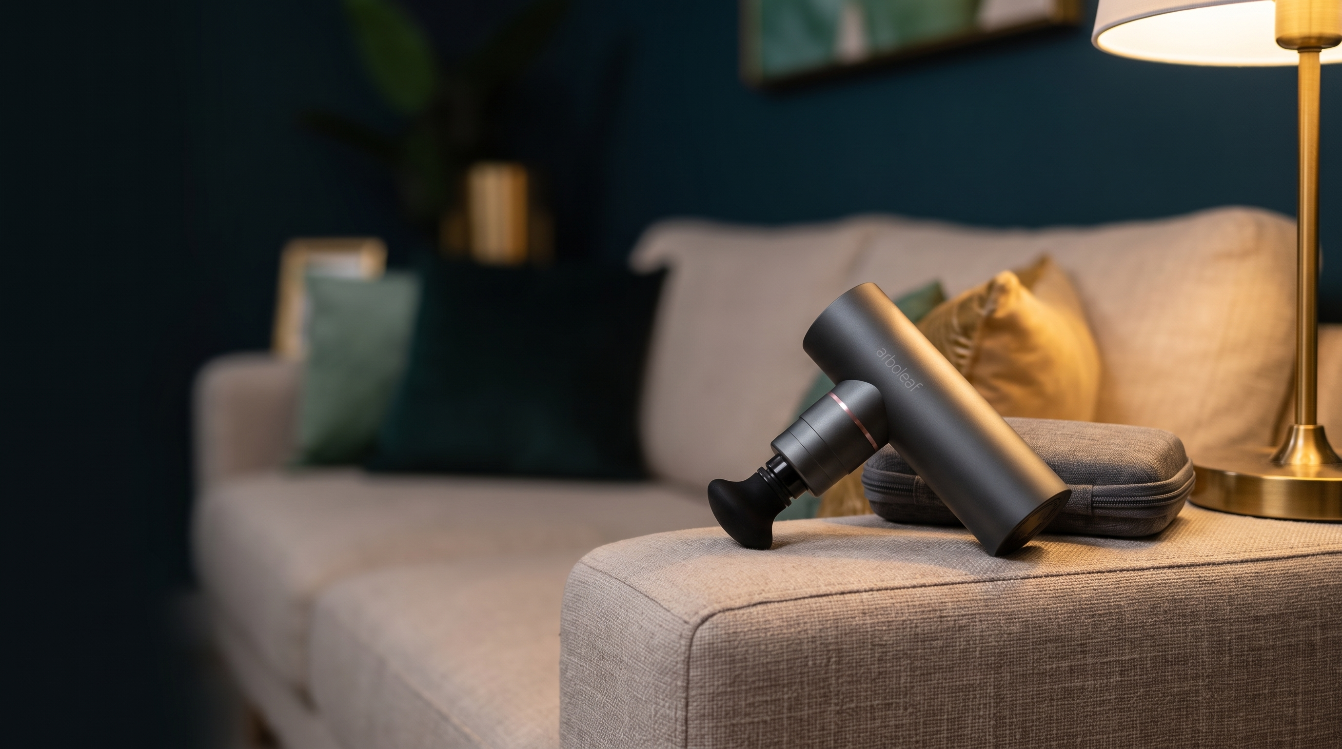 Mini-Massagepistole von arboleaf auf einem hellen Sofa neben der Transporttasche