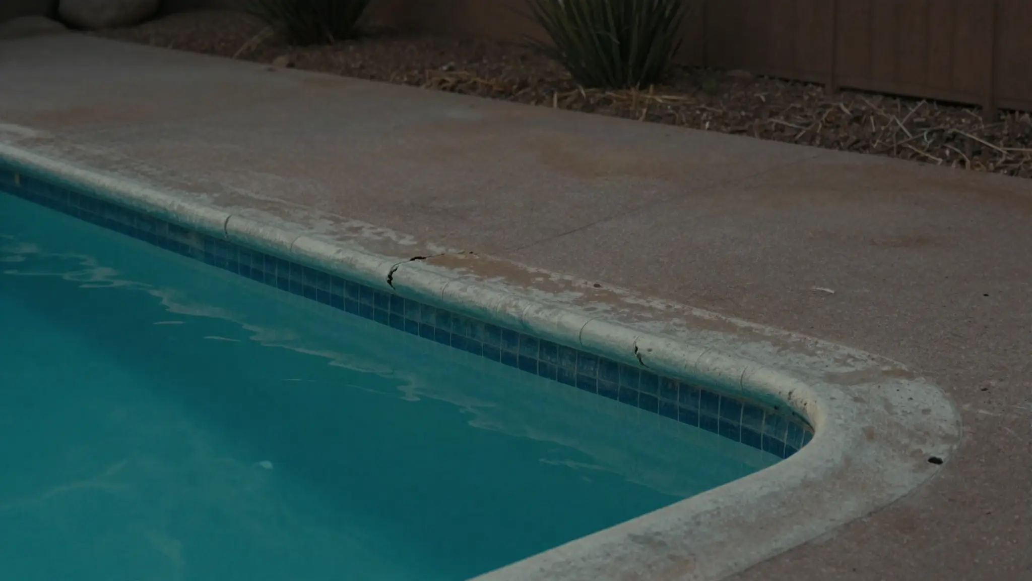 what causes pool leaks — an aging Arizona backyard pool showing signs of wear