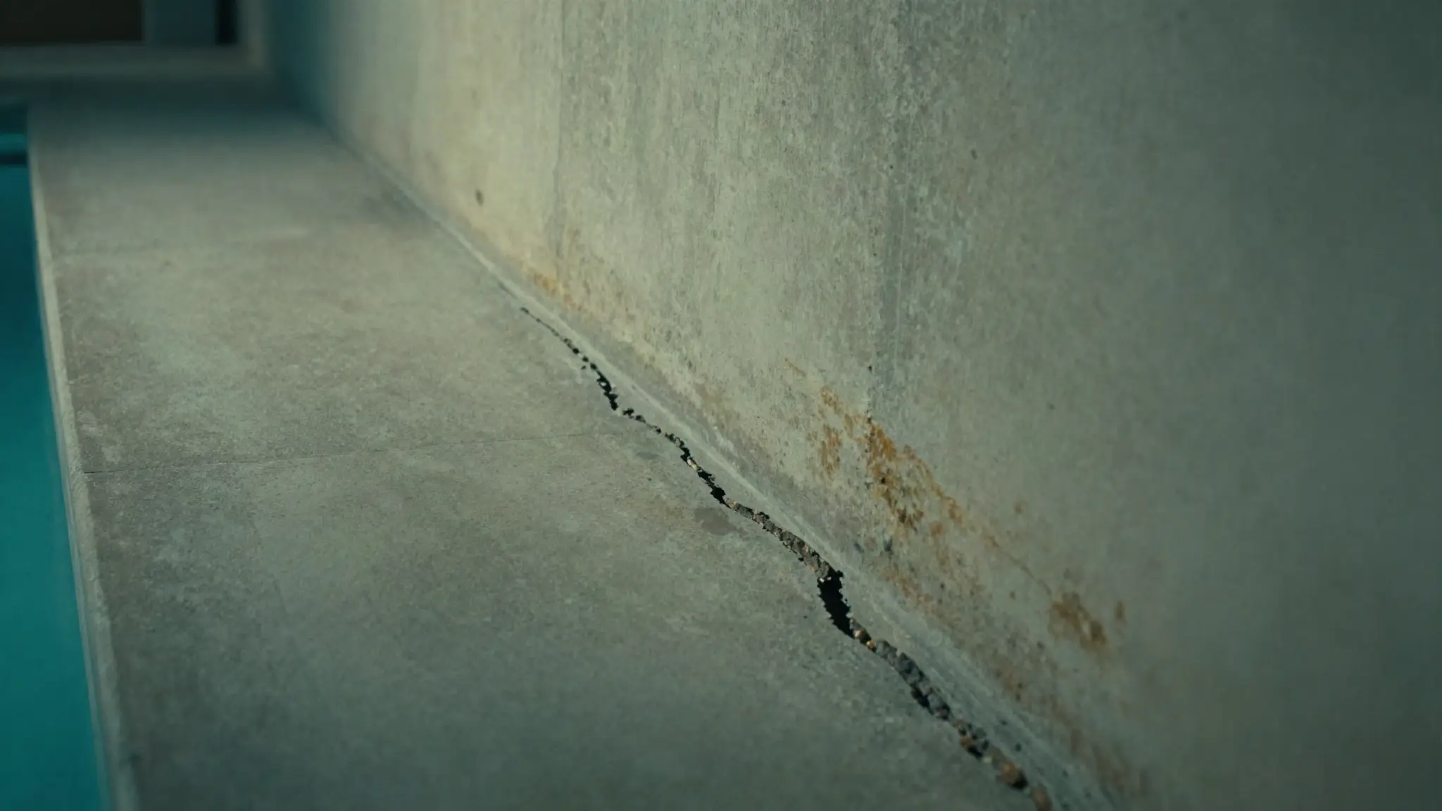 structural crack running across a concrete pool shell floor and wall