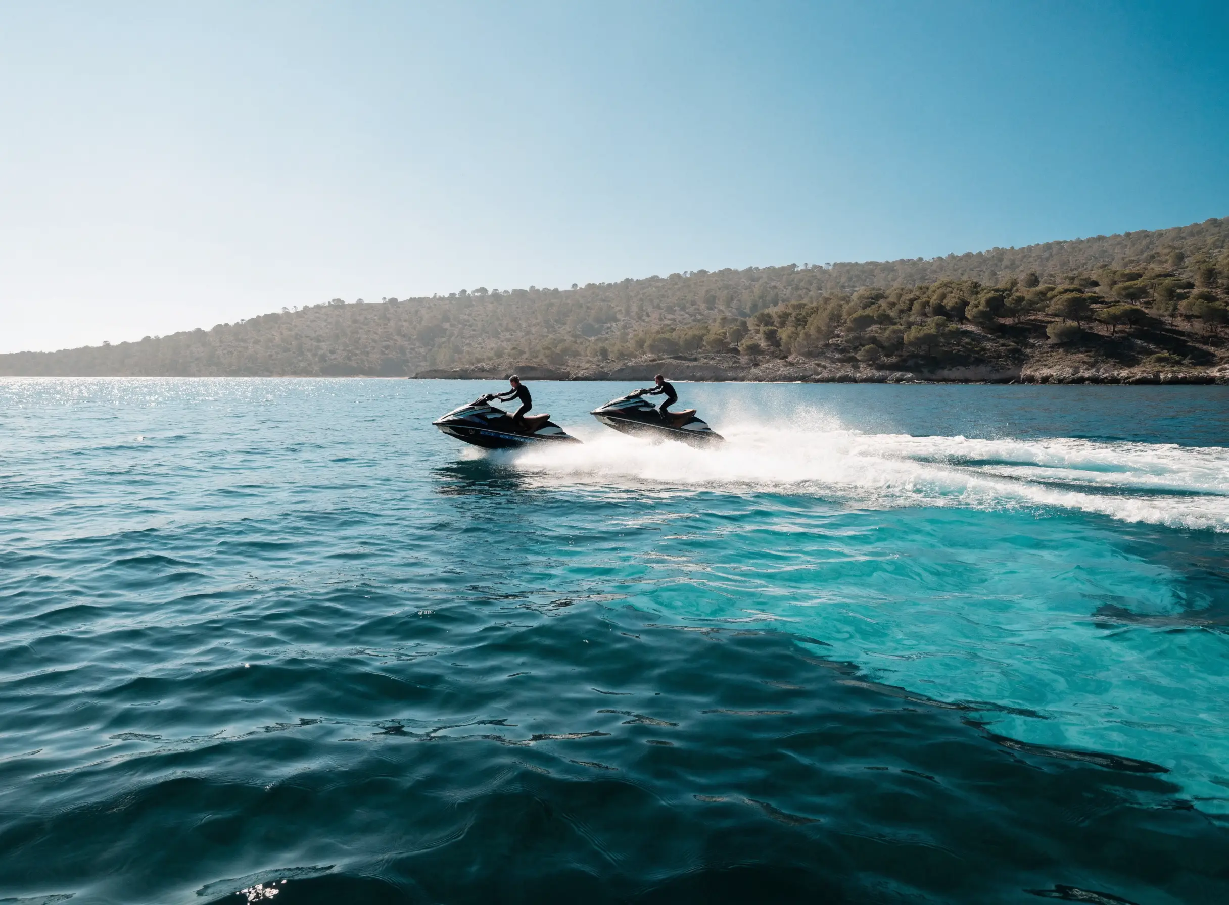 Two people riding jet skis side by side on open water