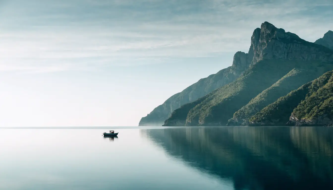 A boat anchored off the coast below green mountains