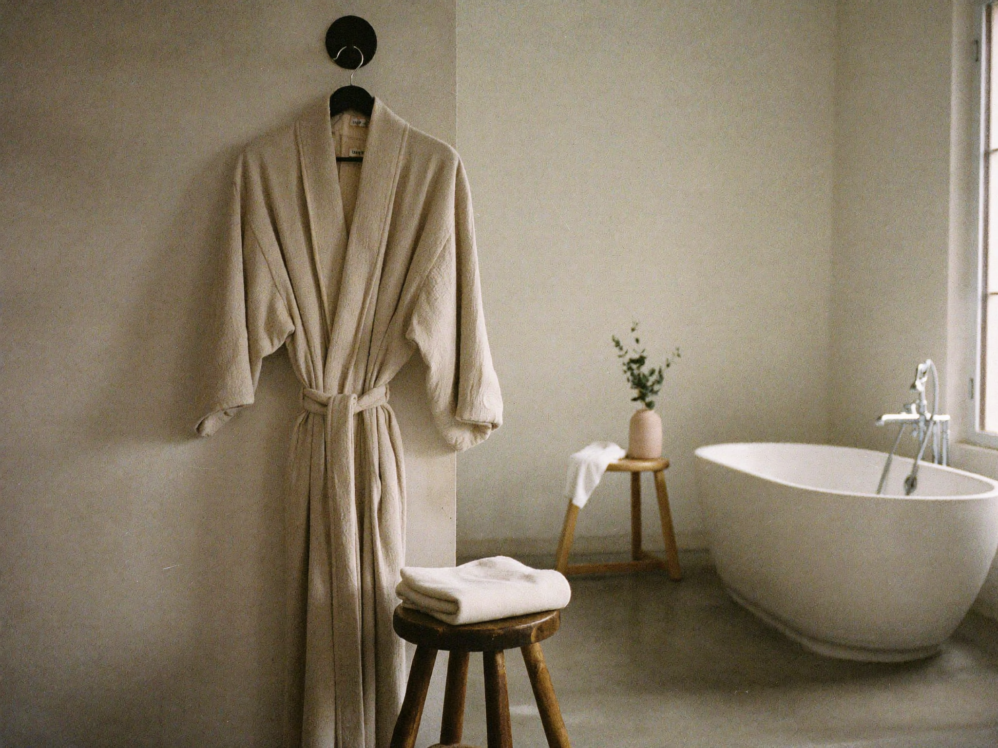 Salle de bain épurée avec un peignoir suspendu, ambiance spa