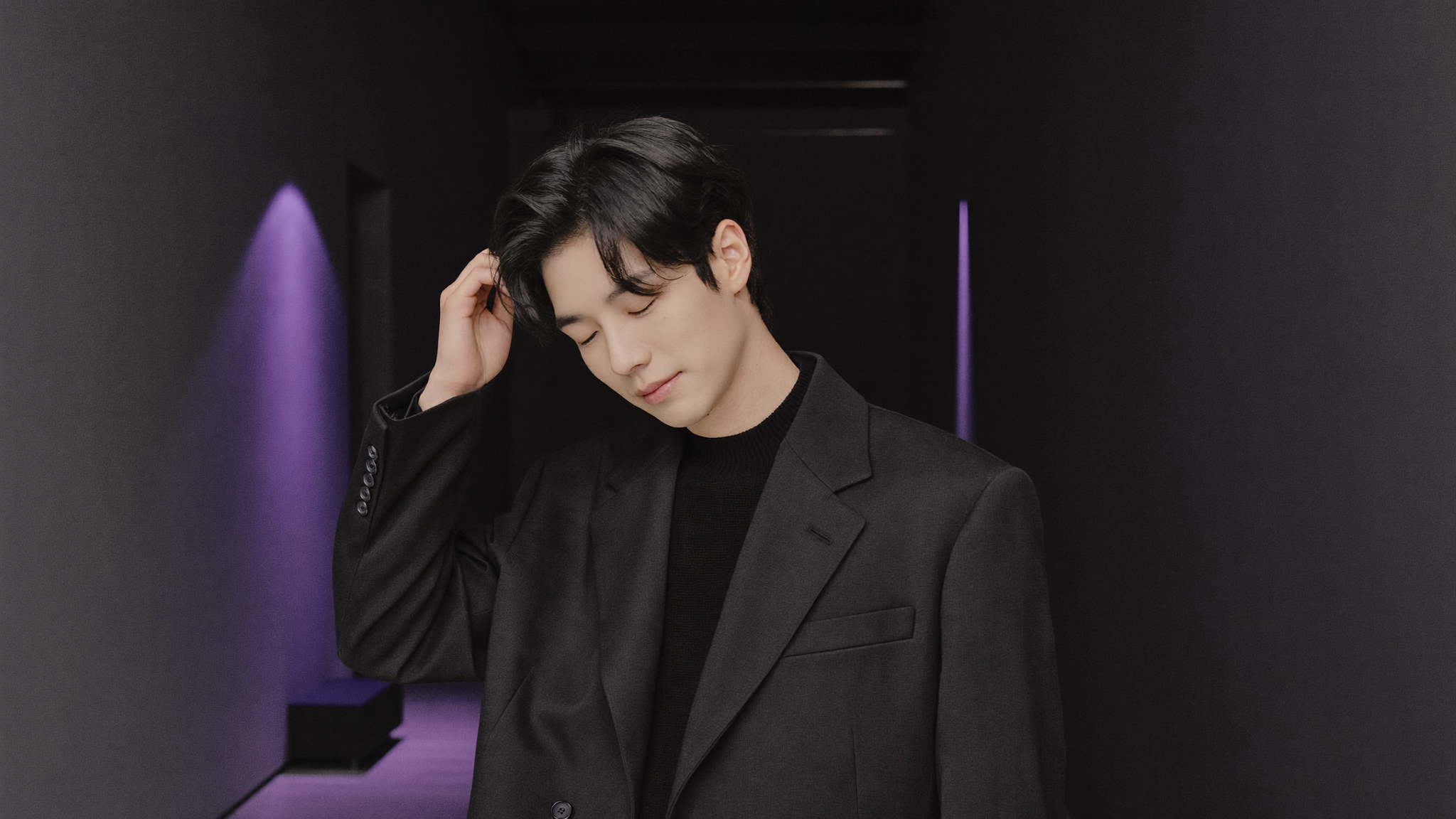 미니멀한 복도에 서 있는 블랙 니트 차림의 매니저