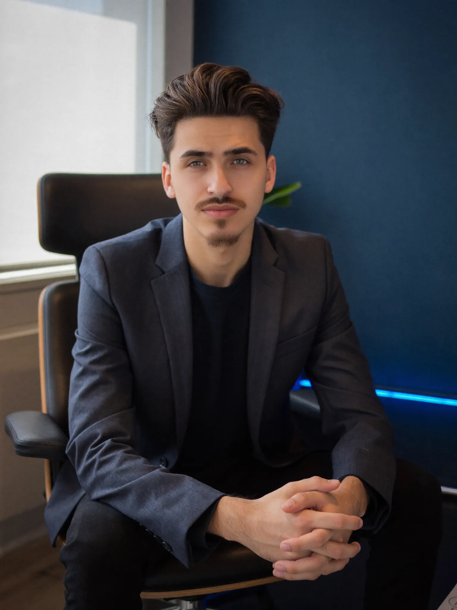 Daniel, founder of Progon Services, seated in a modern office with blue accent lighting