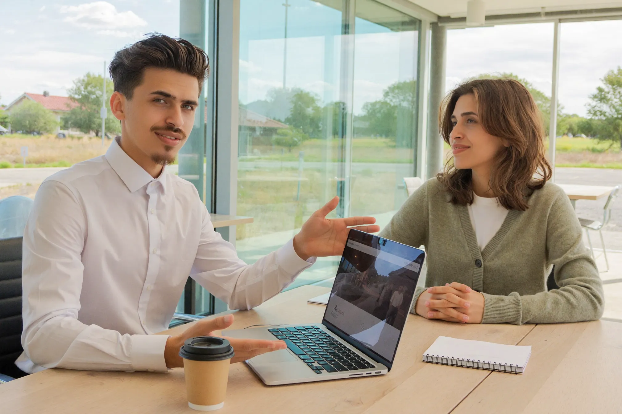 Daniel walking a client through a new website design on a laptop in a bright modern meeting room