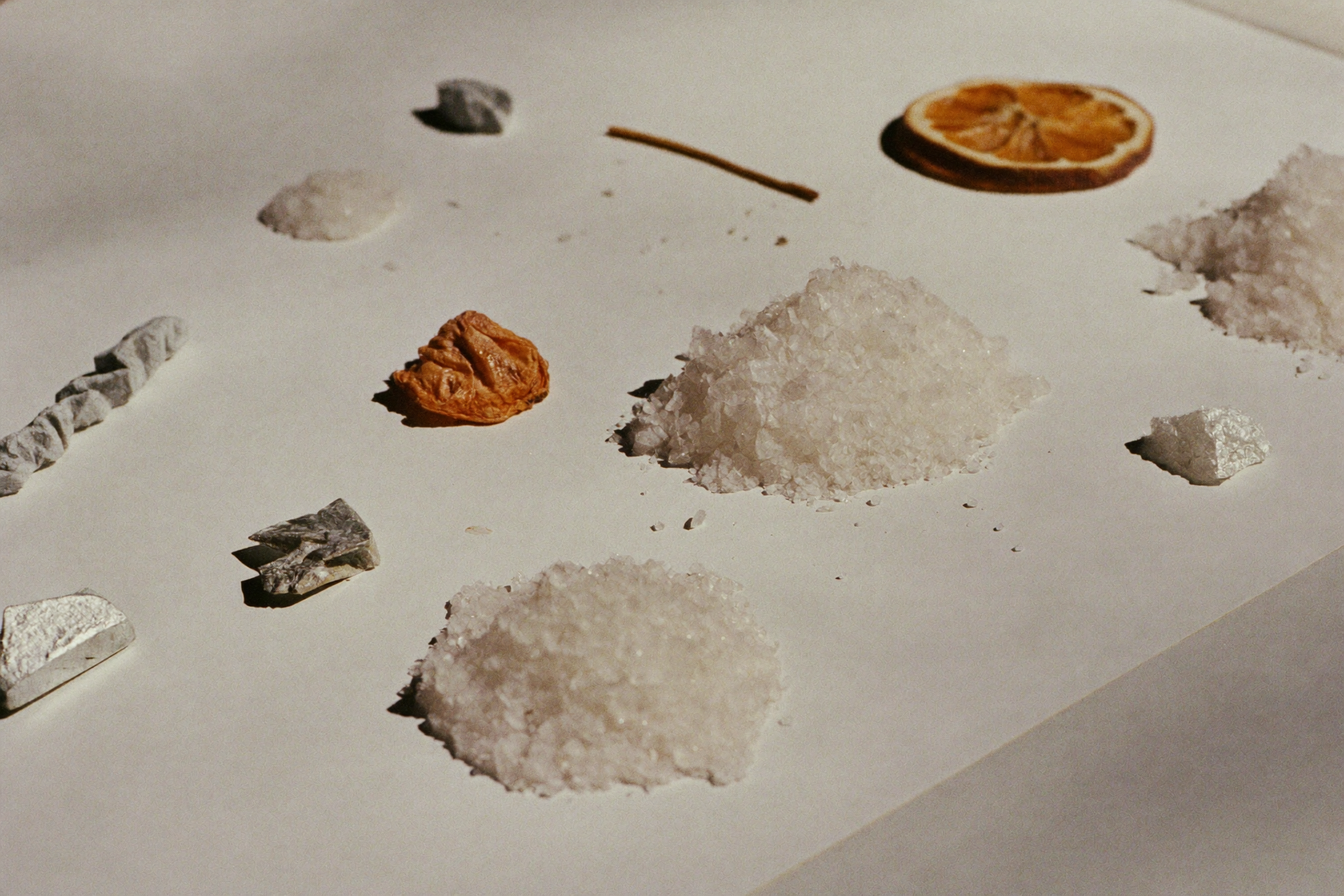 Macro specimens of salt crystals, mineral grains and citrus on a pale surface