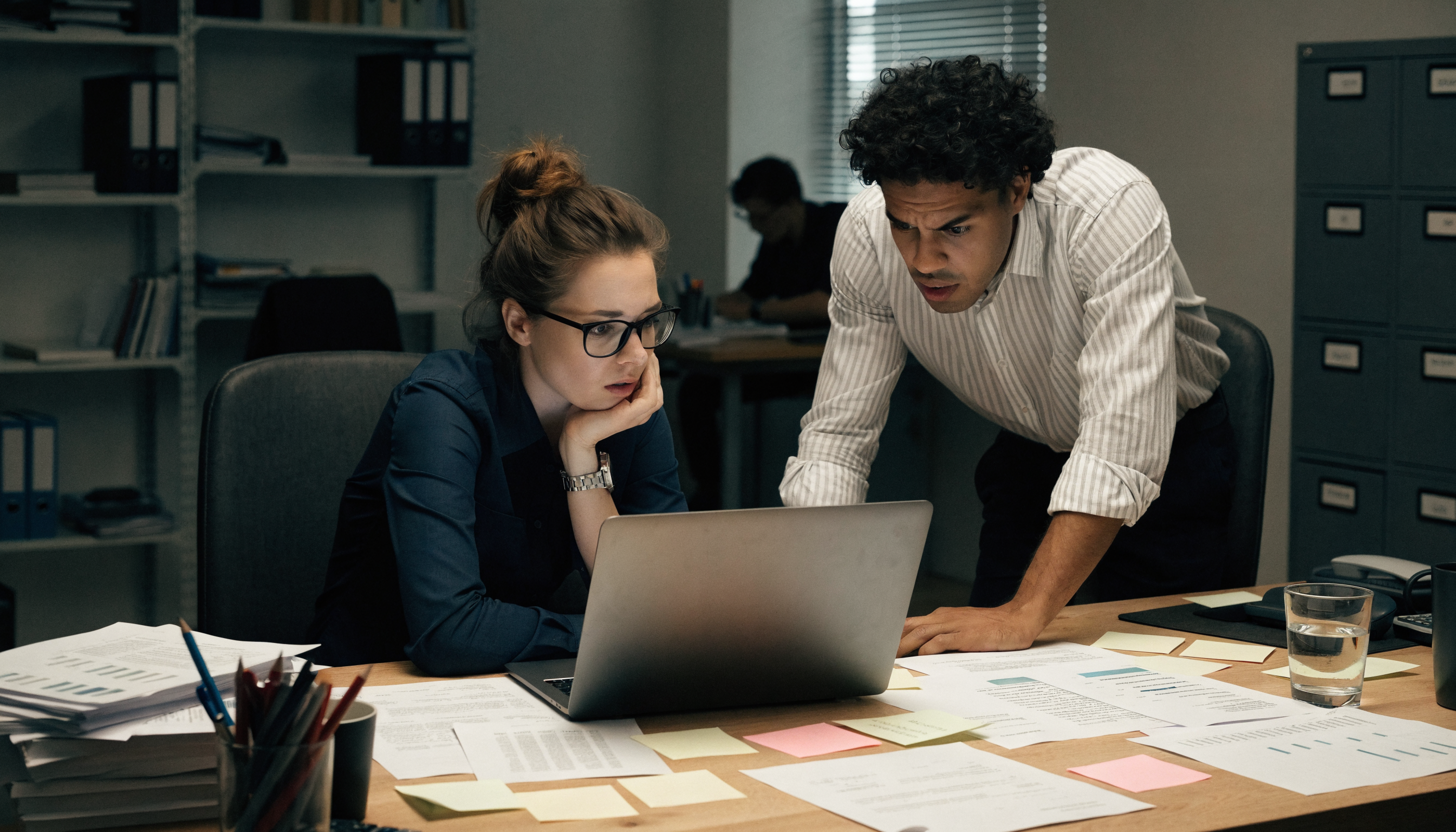 Gefrustreerd team achter een rommelig bureau tijdens een vastgelopen project