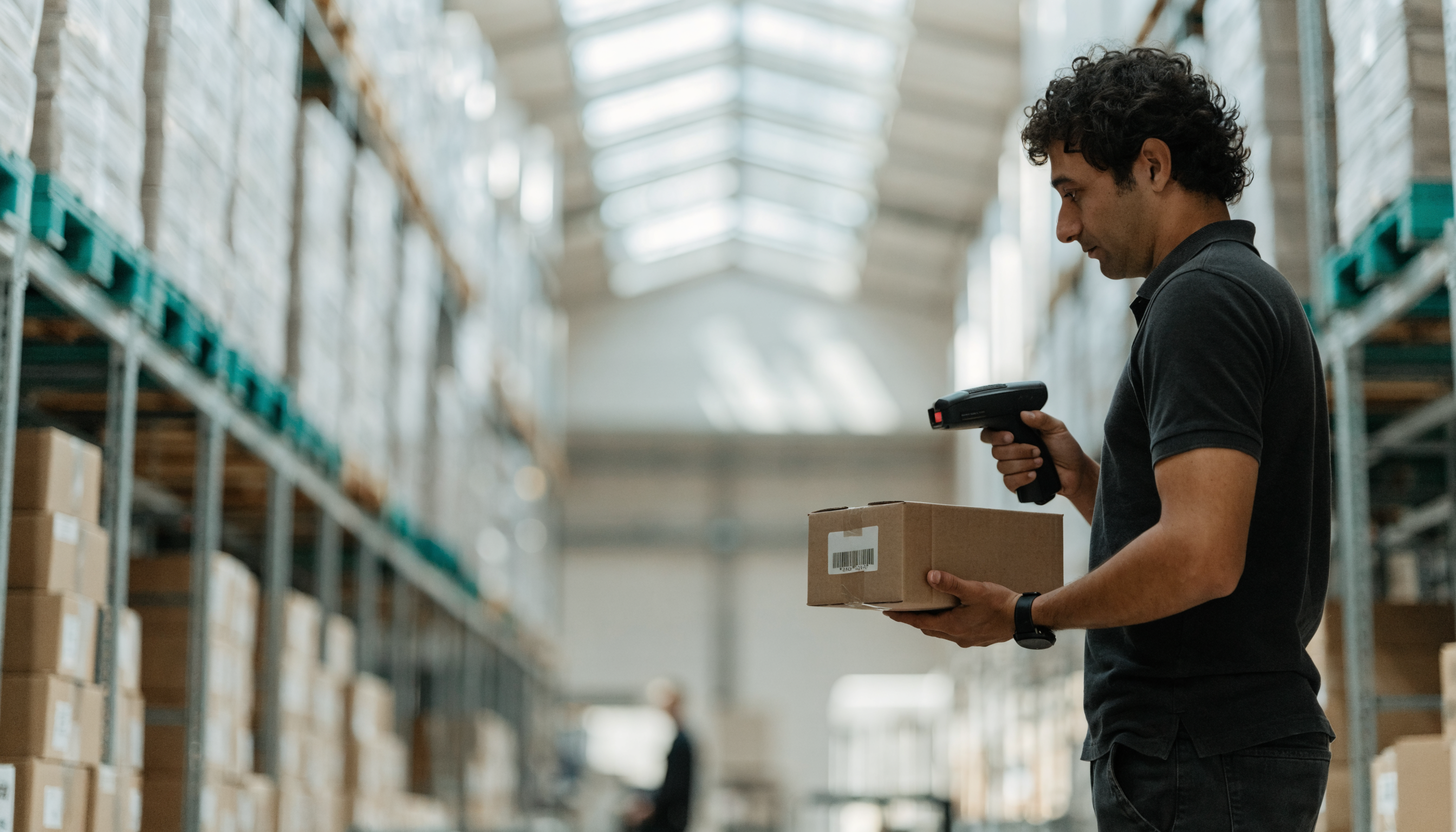 Magazijnmedewerker scant een barcode tussen hoge stellingen