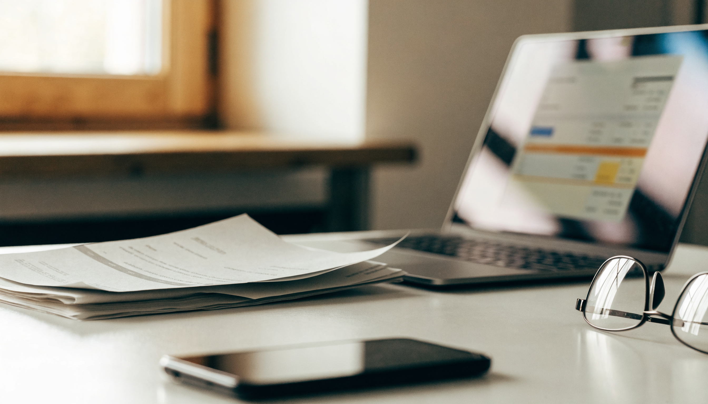 Bureau met papieren facturen die digitaal worden verwerkt