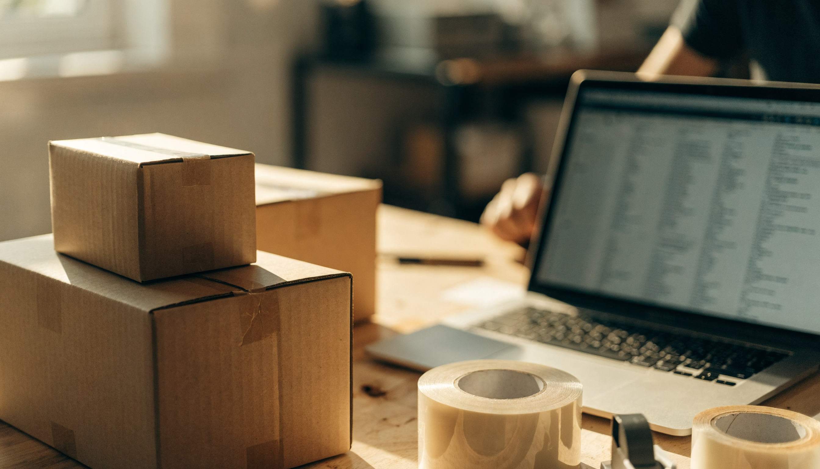 Inpakstation met dozen en tape in een e-commerce magazijn