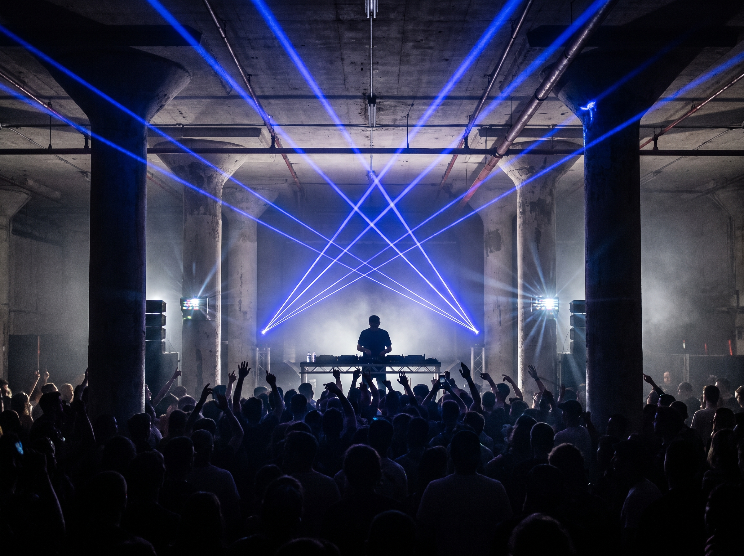 DJ set with blue lasers over a dancing crowd