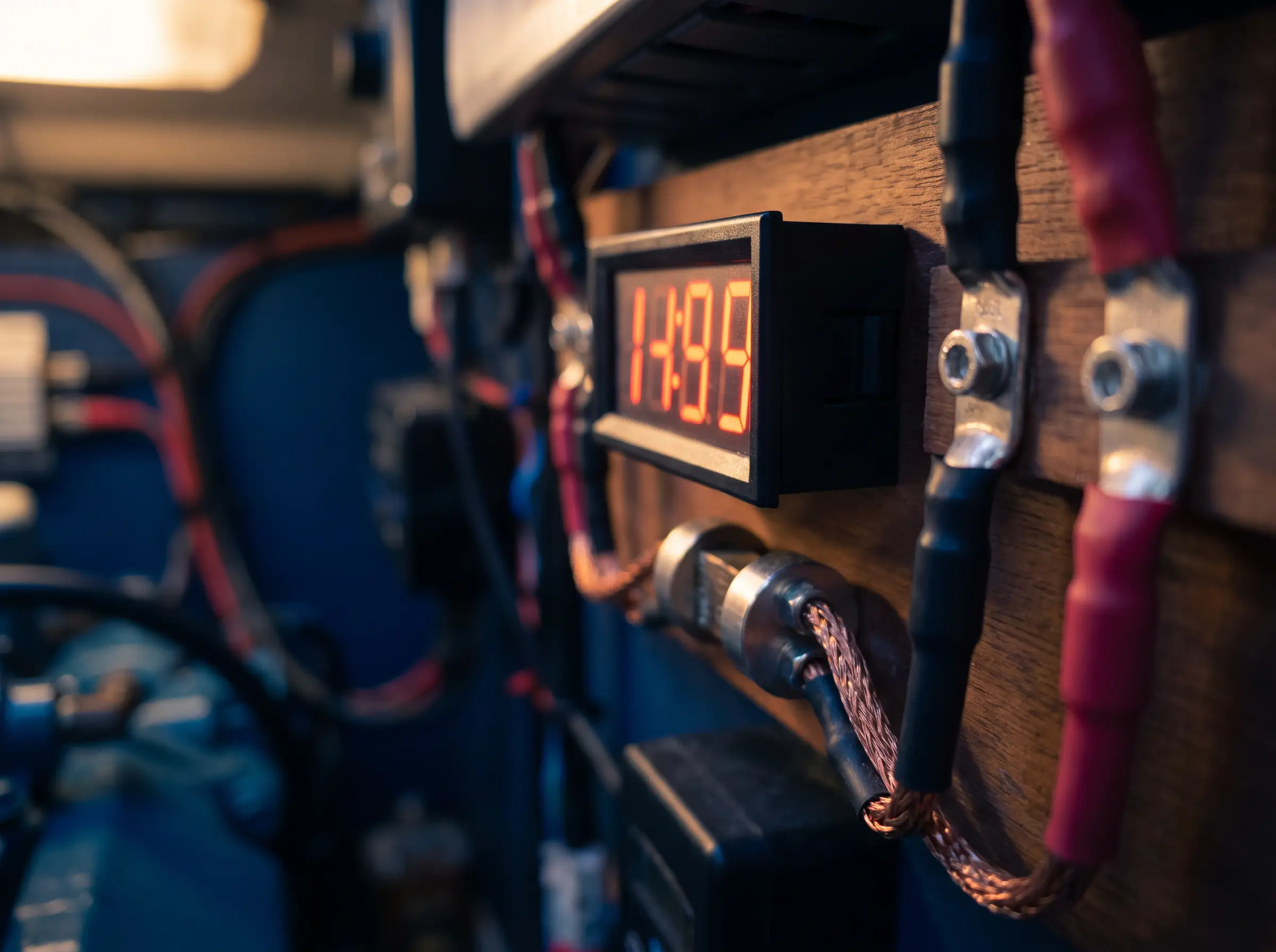 Battery monitor shunt and state-of-charge display glowing softly beside clean tinned copper lugs