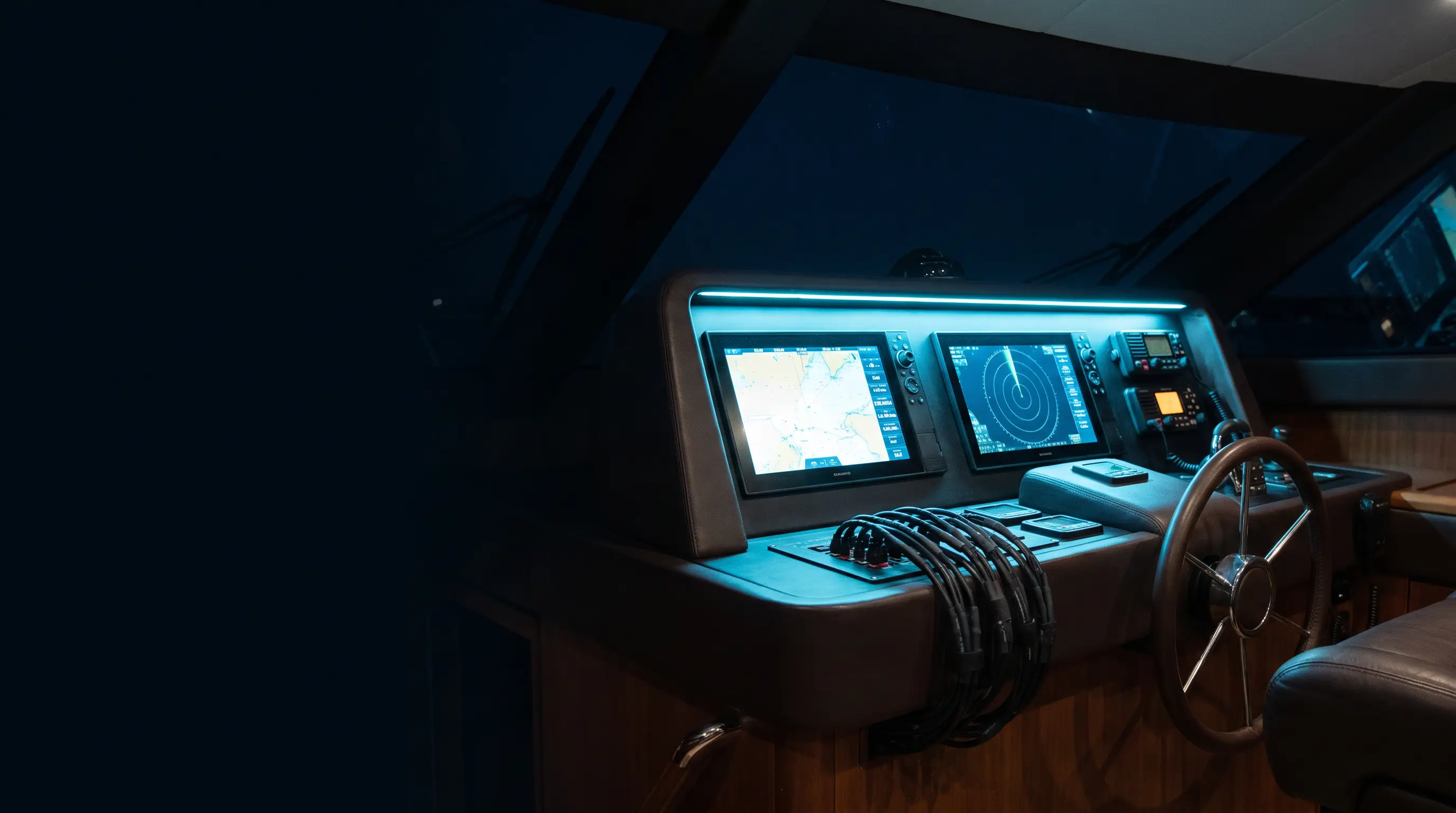 A boat's helm station at night with freshly installed chartplotter, radar, and VHF glowing in cool blue light