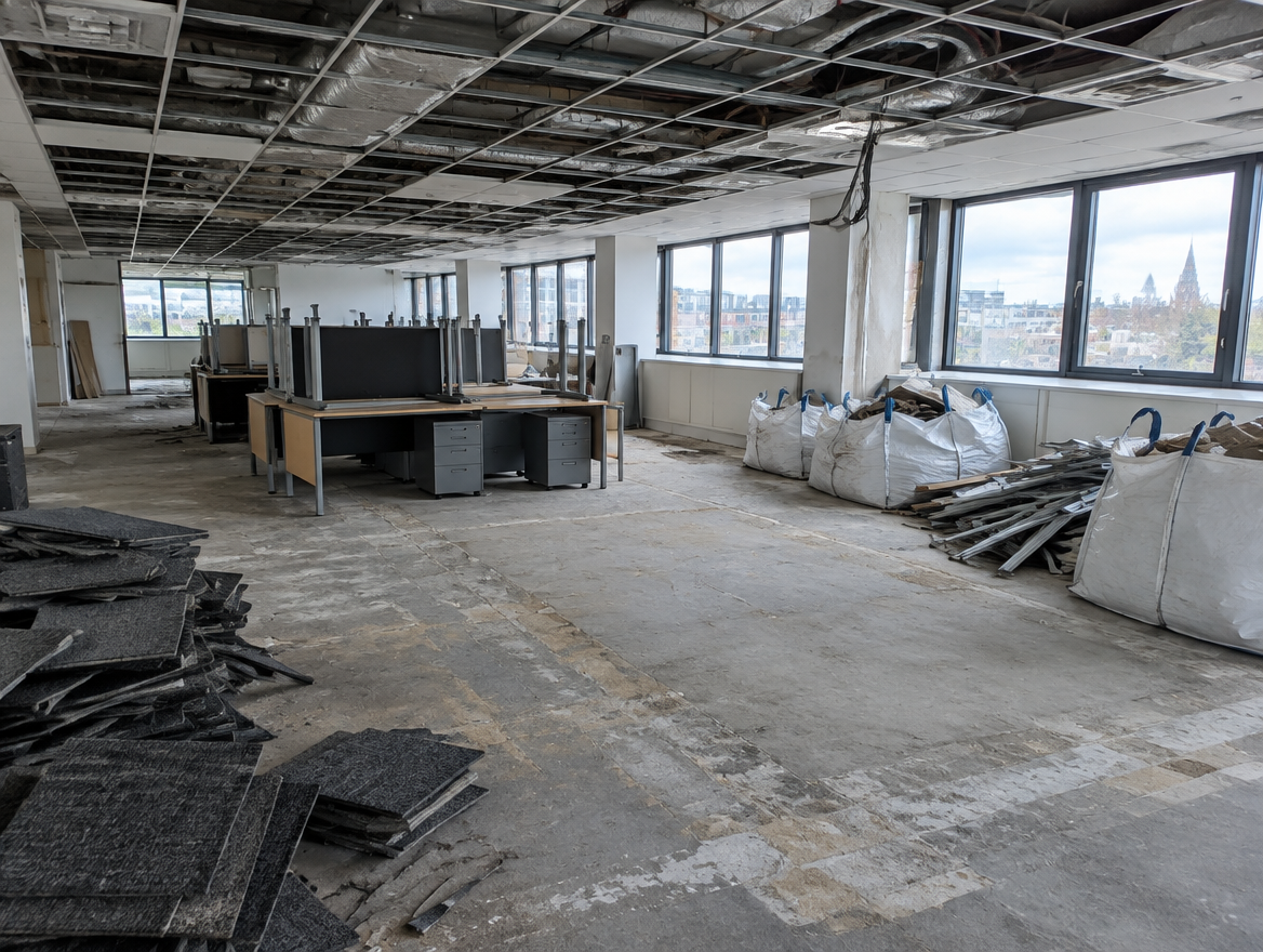 Office floor mid strip-out with ceiling tiles removed and waste bagged
