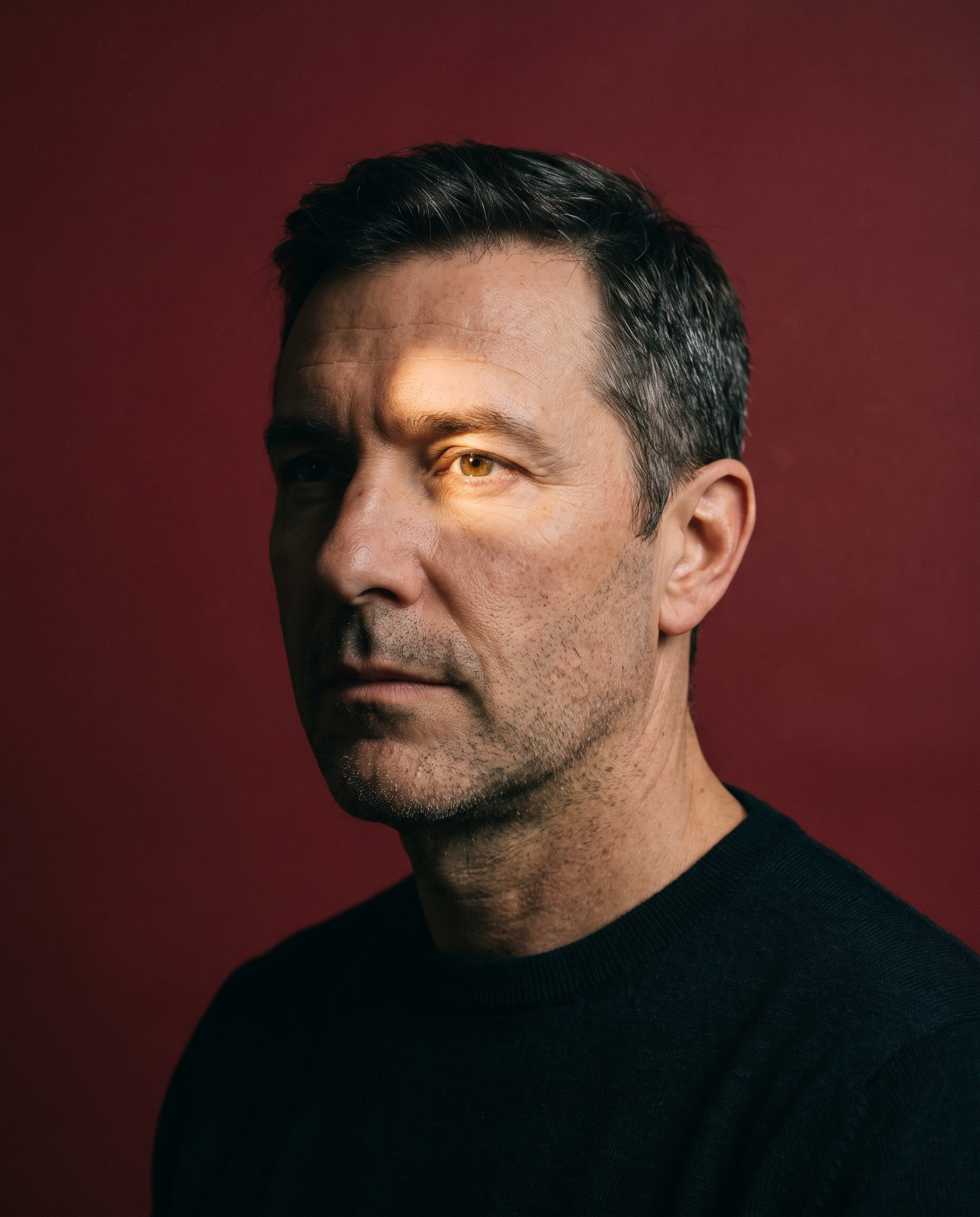 A man in three-quarter profile, half his face in shadow