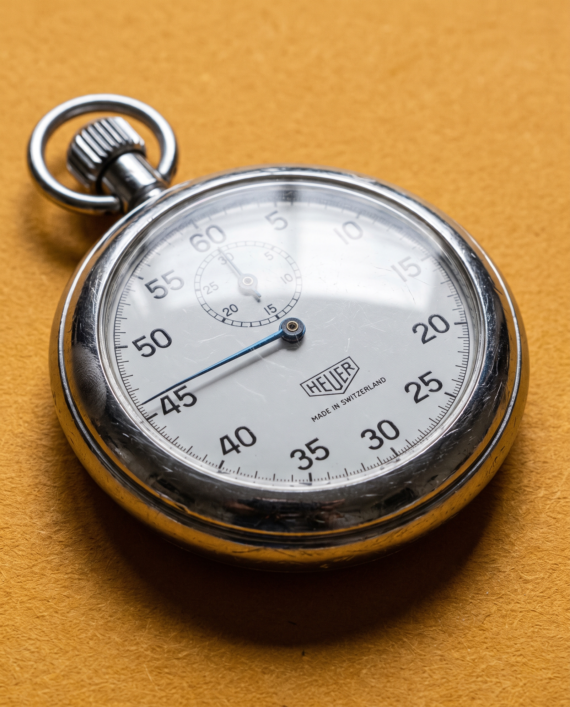 Macro of a chrome mechanical stopwatch on amber paper