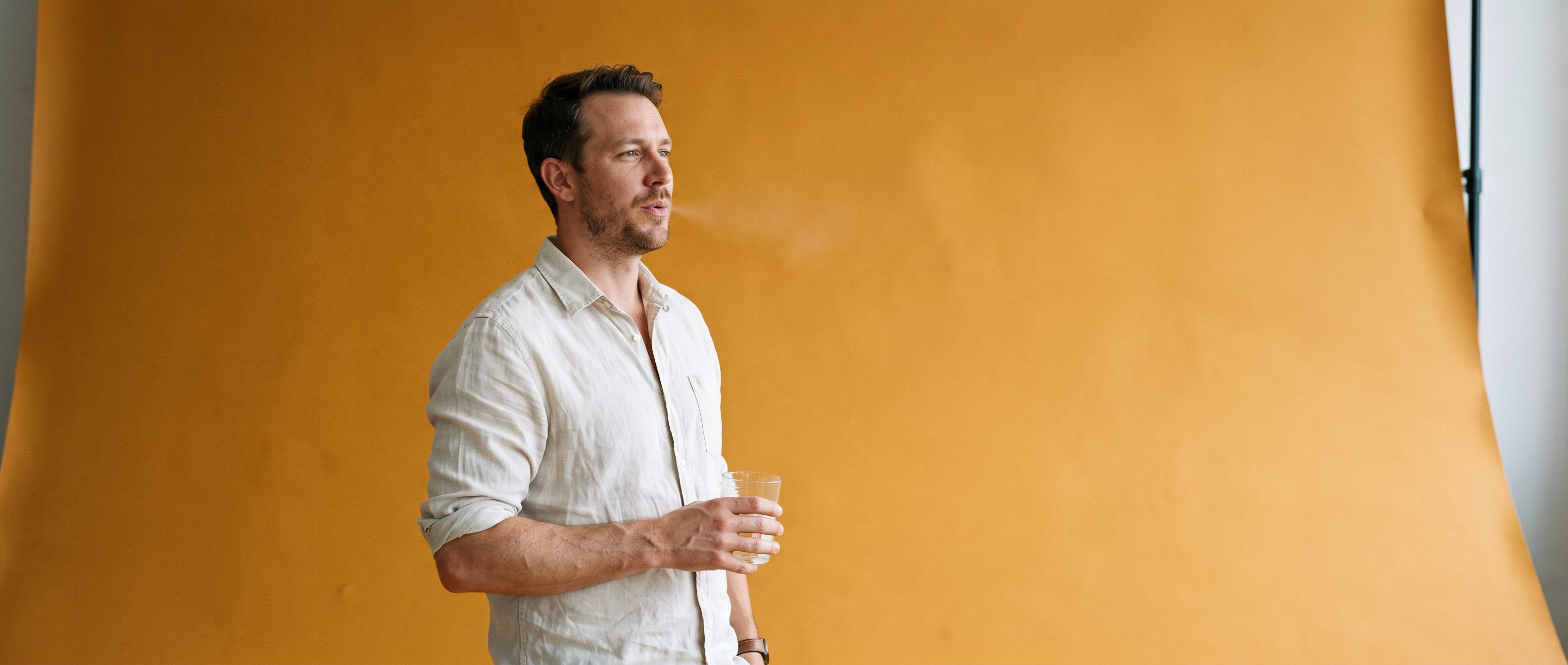 A man at the left of a wide open amber sweep holding a glass of water
