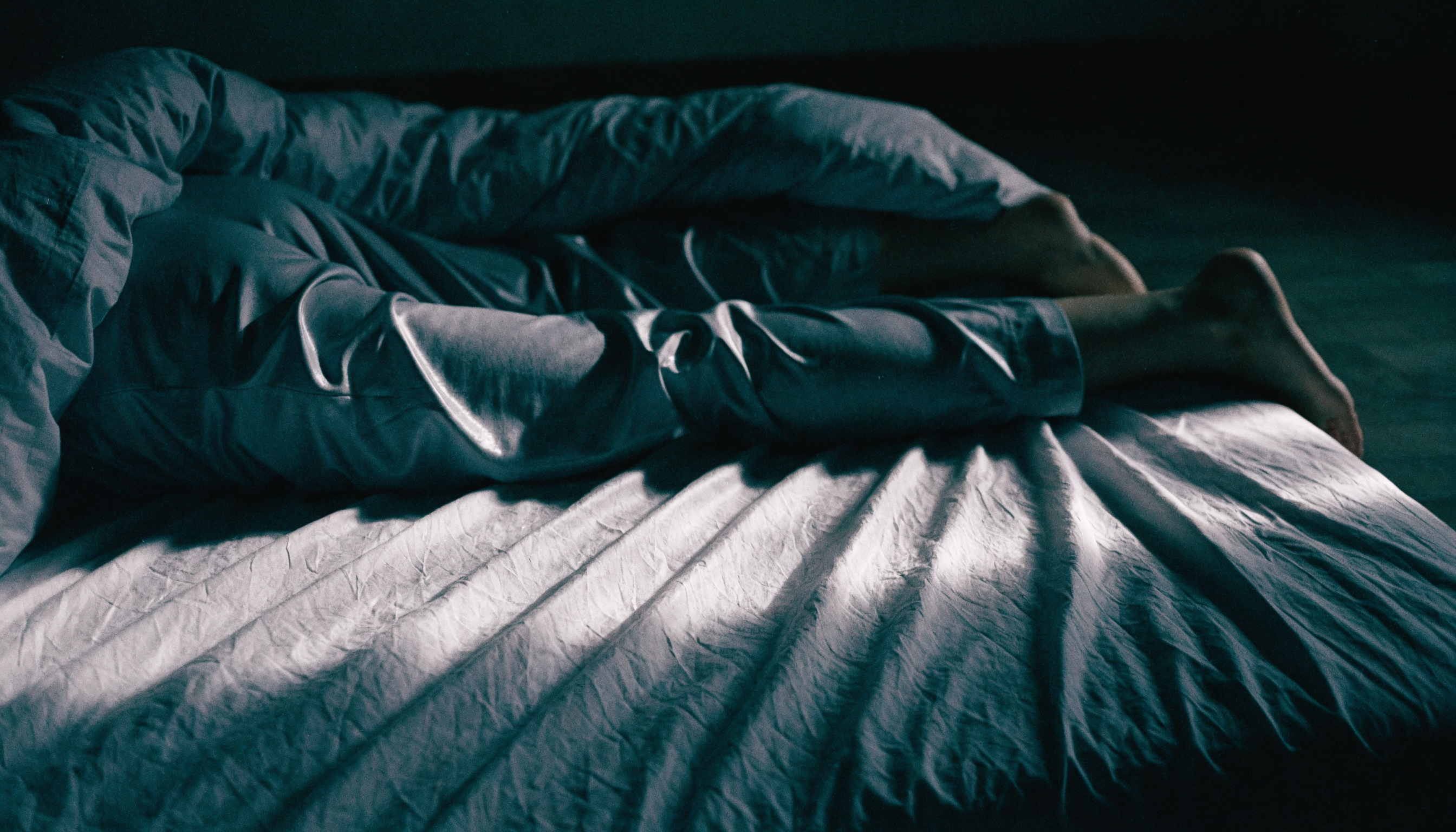 Synthetic pyjama trousers, one leg pushed out from under the duvet at night