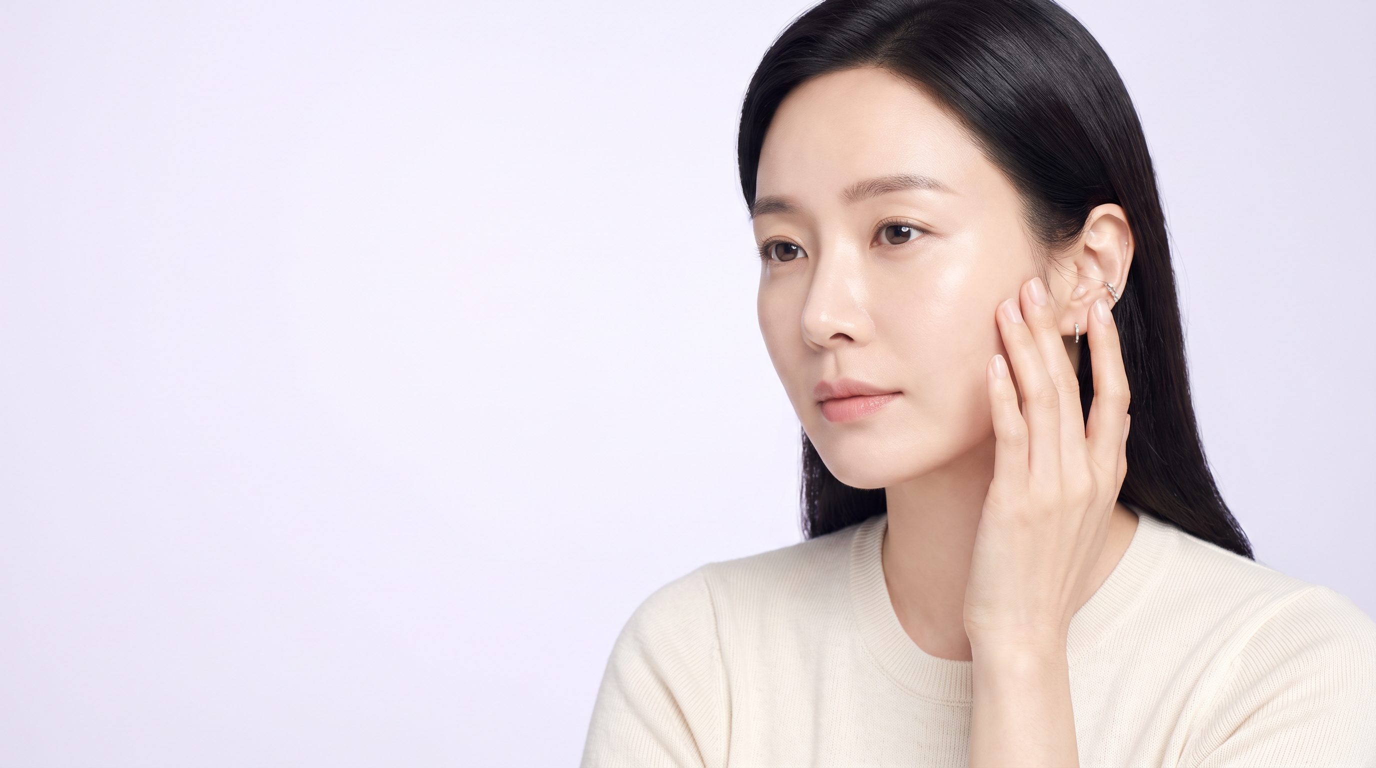 볼을 손끝으로 살짝 들어 올리며 처짐을 확인하는 30대 한국 여성